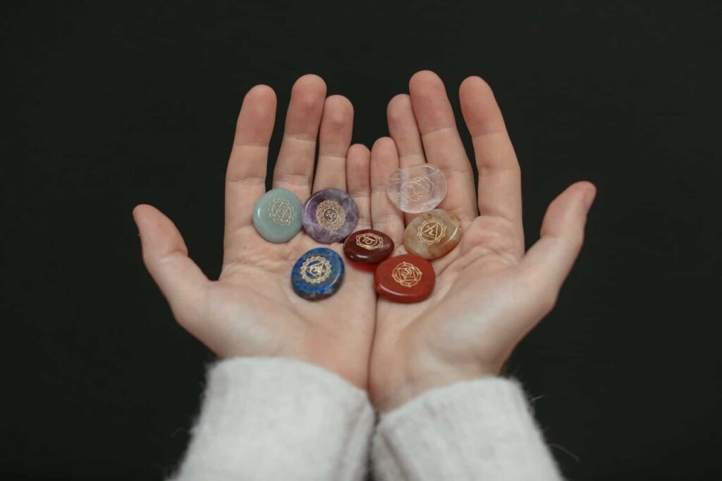 Hands holding 7 chakra stones.