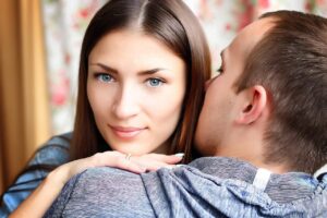 Man whispering in Libra woman's ear - flirting can be a Libra toxic trait.
